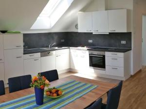 a kitchen with white cabinets and a table with a bowl of fruit at Beech Modern Retreat in Hödingen
