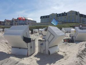 a group of white chairs in the sand on a beach at The Blue House Modern retreat in Wangerooge