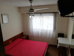 a bedroom with a red bed and a window at Necochea Real Hotel in Necochea