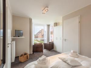 a white bedroom with a bed and a television at Dünenhuus Ost Modern retreat in Juist