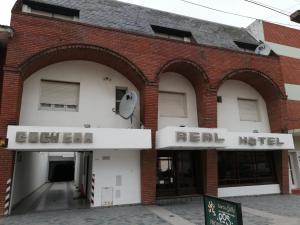 内科切阿Necochea Real Hotel的一座红砖建筑,上面有真正的汽车旅馆标志