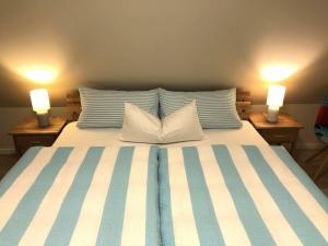 a bed with blue and white striped sheets and two lamps at Holiday home Wiedblick in Neu Gaarz