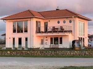 a pink house with a balcony on top of it at To"n Lüchtfüer Comfortable holiday residence in Dwarsdorf