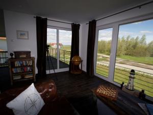 a living room with a couch and large windows at To"n Lüchtfüer Comfortable holiday residence in Dwarsdorf