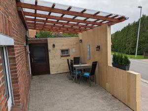 a patio with a table and chairs under a wooden pergola at Huus Meta Modern retreat in Krummhörn