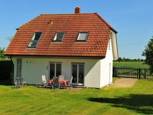 a white house with a table and chairs in the yard at Holiday home Crane Coast in Kinnbackenhagen +19 photos