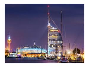 a city at night with a large building and boats at Gießler Comfortable holiday residence in Bremerhaven