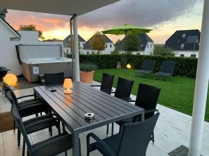 un tavolo in legno con sedie e un ombrellone su un patio di Haus Seeblick Modern retreat a Göhren-Lebbin