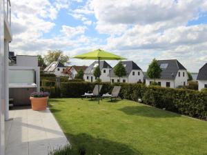 un patio con una sombrilla verde y sillas en Haus Seeblick Modern retreat, en Göhren-Lebbin