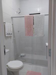 a bathroom with a glass shower with a toilet at Porto Belo Perequê in Porto Belo
