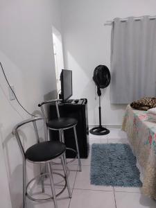 a room with two chairs and a television and a bed at Porto Belo Perequê in Porto Belo