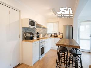 een keuken met witte kasten en een houten tafel bij Homeski in Jindabyne +13 foto's