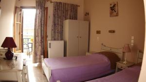 a bedroom with a purple bed and a refrigerator at Filia Rooms in Matala
