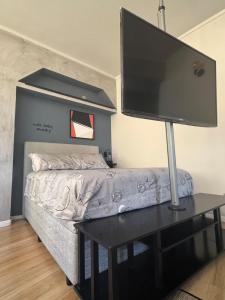 a flat screen tv on a table with a bed at Kitnet 1109 in São Vicente