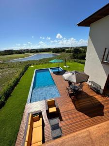 a backyard with a swimming pool and an umbrella at Casa Temporada Praia do Forte, Complexo Iberostate, 5 Suítes in Praia do Forte