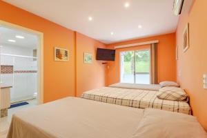 two beds in a room with orange walls at Mansão Santa Tereza delux in Rio de Janeiro +23 photos