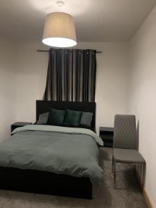 a bedroom with a bed and a chair and a lamp at Serenity-ESE Entire Home in Basildon