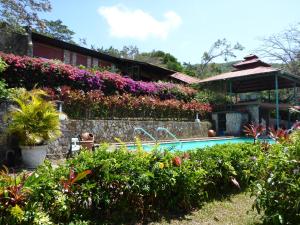 una casa con piscina y flores en The Golden Frog Inn, en El Valle de Antón