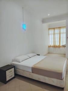 a white bedroom with a bed and a night stand at Pearl Villa 5 Bedroom Unit 1 in Port Dickson