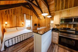 a bedroom with a bed and a kitchen in a cabin at Peaceful Creekside Tiny Cabin, Family Adventure Near Waterfalls in Smithville
