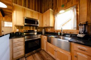a kitchen with wooden cabinets and a stainless steel sink at Cozy Creekside Cabin Near Waterfalls, Hiking, Fire Pit in Smithville