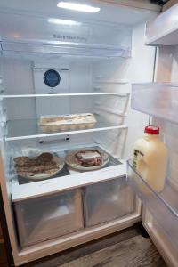 ein offener Kühlschrank mit Lebensmitteln und einer Gallone Milch in der Unterkunft Waterfall Getaway Tiny Cabin Near Rock Island Cabin 1 in Smithville + 23 Fotos
