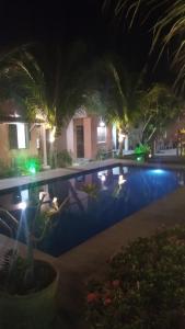 a night view of a swimming pool at a resort at El Farol Bistrô e Pousada in Fortim