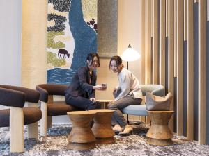 dos mujeres sentadas alrededor de una mesa en una habitación en Richmond Hotel Obihiro Ekimae, en Obihiro