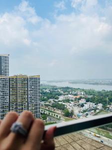 une personne regarde par une fenêtre dans une ville dans l'établissement May Homes - Studio Beverly Vinhomes Grand Park, à Long Bình