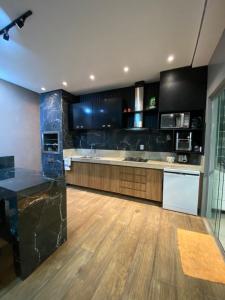 a large kitchen with black cabinets and a wooden floor at Casa condomínio COP30 Arbre in Ananindeua