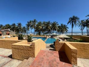 a resort with a pool and palm trees and the ocean at Manolo IV,playa y relajacion in Tucacas