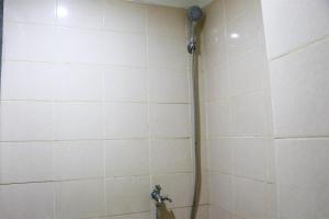 a shower with a hose in a white tiled bathroom at Modern and Nice Studio at Titanium Square Apartment By Travelio in Jakarta +12 photos