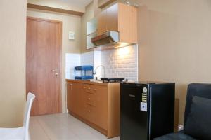 a kitchen with a black refrigerator and a sink at Modern and Nice Studio at Titanium Square Apartment By Travelio in Jakarta