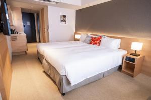 a hotel room with a large bed with white sheets and red pillows at KABIN Taka in Kyoto