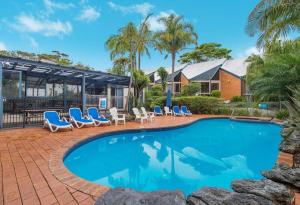 a swimming pool with lounge chairs and a house at Shelly Beach Resort in Port Macquarie