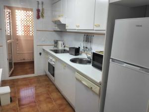 a white kitchen with a sink and a refrigerator at Isla Canela Beach & Golf in Ayamonte