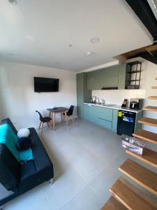 Una sala de estar con un sofá negro y una cocina. en Comfy Loft Centro Histórico, en Cuenca 7 fotos más
