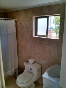 a bathroom with a toilet and a window and a tub at Hostal del Valle in Santa Cruz