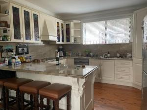 une cuisine avec des placards blancs et un grand îlot avec des tabourets de bar dans l'établissement Church House - Warimoo large living and games room, à Warrimoo