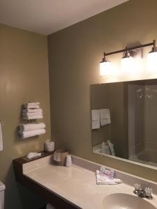 a bathroom with a sink and a mirror and towels at Sunlac Inn Devils Lake in Devils Lake