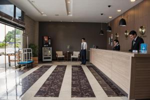 um lobby com dois homens de pé em um balcão em Hotel Estação 101 - Itajaí em Itajaí