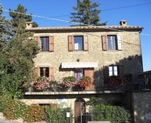 Cette maison en pierre dispose d'un balcon et de fleurs. dans l'établissement La Morosa, à Castel Rigone