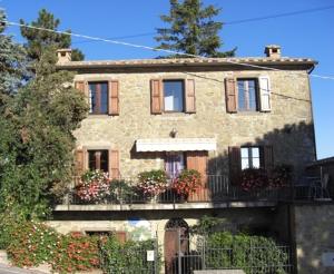 uma casa de pedra com uma varanda e flores nela em La Morosa em Castel Rigone