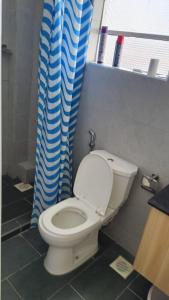 baño con aseo y cortina de ducha azul en The Crib House 254, en Kitengela 