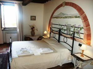 una camera da letto con un grande letto bianco e un dipinto sul muro di La Morosa a Castel Rigone