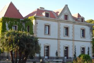 a large white house with a palm tree in front of it at La Bellonette in Marseillan