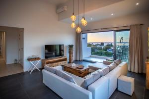 a living room with a white couch and a large window at Modern Penthouse - Sunset, Jacuzzi & Sea Views in Tamarin