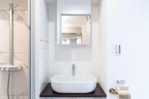 een witte badkamer met een wastafel en een spiegel bij Shinsen Hombe BLD in Tokyo