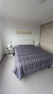 a bedroom with a bed with a comforter on it at Departamento Hermosa Vista Cercano Playa Herradura in Coquimbo
