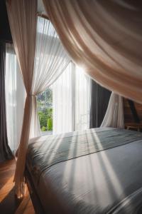 a bedroom with a canopy bed with a window at Desa Cabins in Balian +60 photos